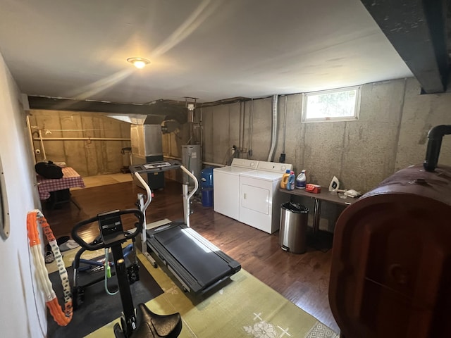 workout room featuring washer and clothes dryer, dark wood finished floors, gas water heater, and heating fuel