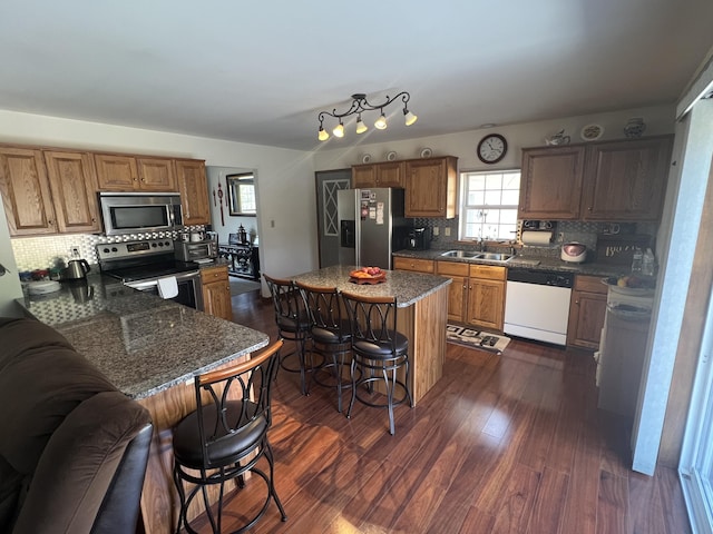 kitchen featuring a breakfast bar, dark wood finished floors, a sink, stainless steel appliances, and backsplash