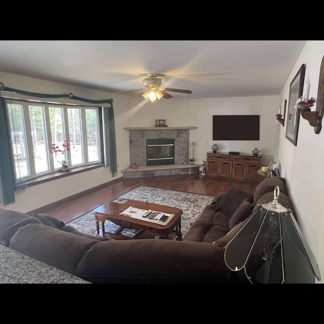 living area with a fireplace, wood finished floors, and a ceiling fan