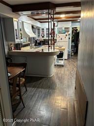 kitchen featuring beamed ceiling, a kitchen breakfast bar, and wood-type flooring