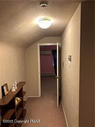 corridor featuring lofted ceiling, light colored carpet, and baseboards