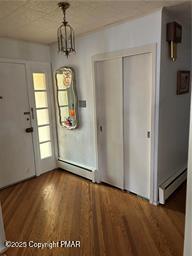 unfurnished dining area with baseboard heating, wood finished floors, and a textured ceiling