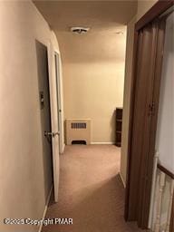 hallway with heating unit, visible vents, and carpet flooring