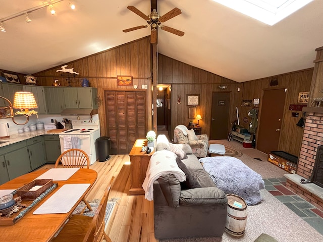 dining room featuring a ceiling fan, wood walls, wood finished floors, and lofted ceiling