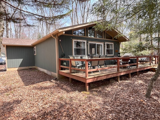 rear view of house featuring roof with shingles and a wooden deck