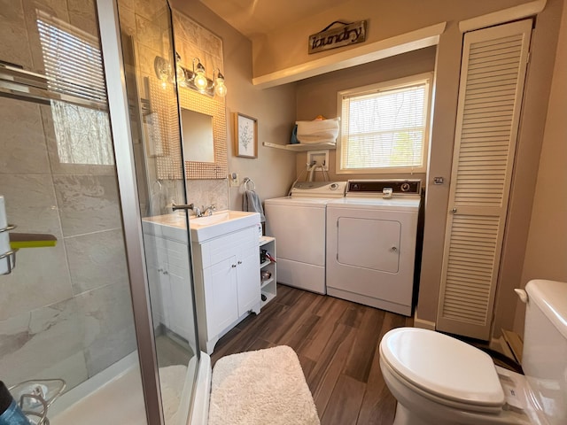 bathroom with a stall shower, washing machine and dryer, wood finished floors, vanity, and toilet