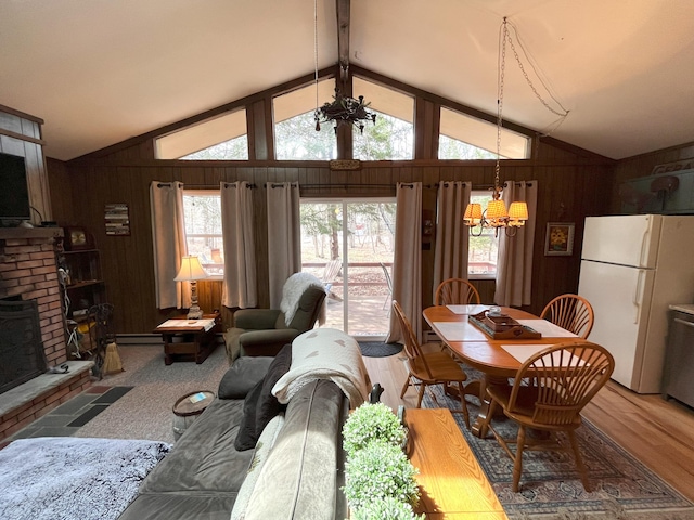 dining area with a fireplace, vaulted ceiling, wood walls, wood finished floors, and a notable chandelier
