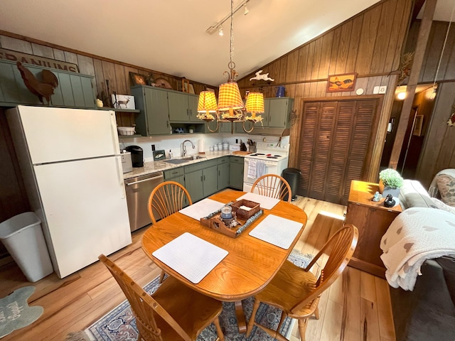 dining space with light wood-type flooring, a notable chandelier, wood walls, and lofted ceiling
