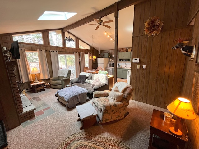 living room featuring lofted ceiling with skylight, wood walls, carpet, and ceiling fan