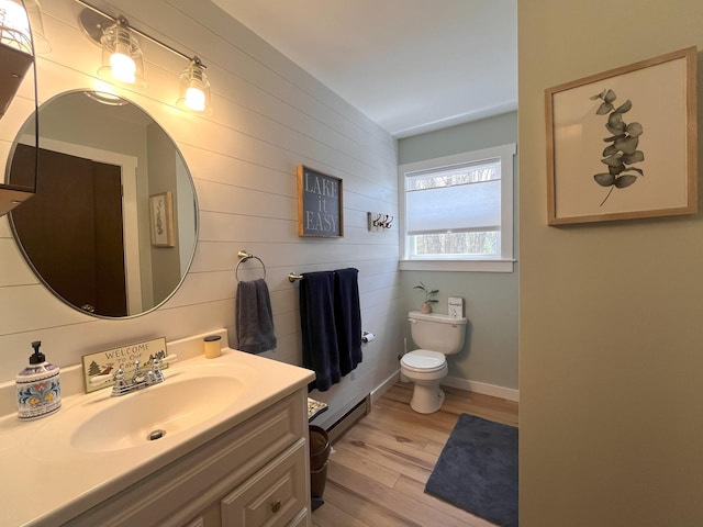 bathroom with vanity, wood finished floors, toilet, baseboards, and a baseboard heating unit