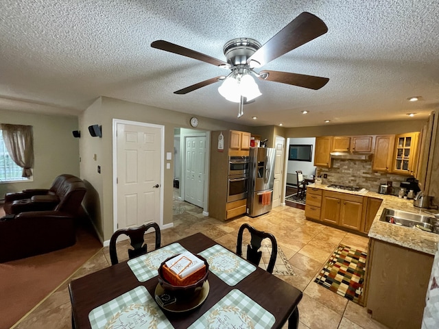 dining space featuring light tile patterned flooring, ceiling fan, a textured ceiling, and baseboards