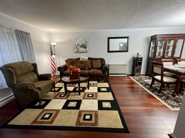 living area with a textured ceiling, ornamental molding, baseboard heating, and dark wood finished floors