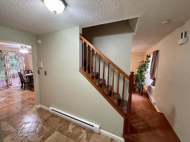 stairway featuring a textured ceiling, baseboard heating, and baseboards