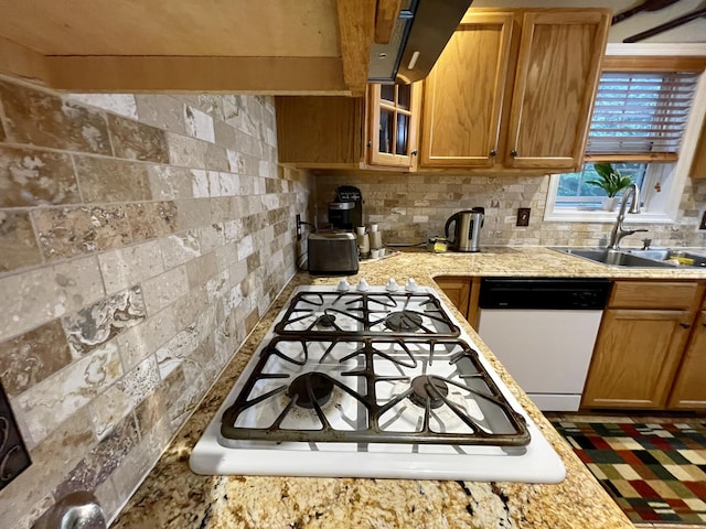 kitchen with light stone counters, tasteful backsplash, glass insert cabinets, a sink, and white appliances