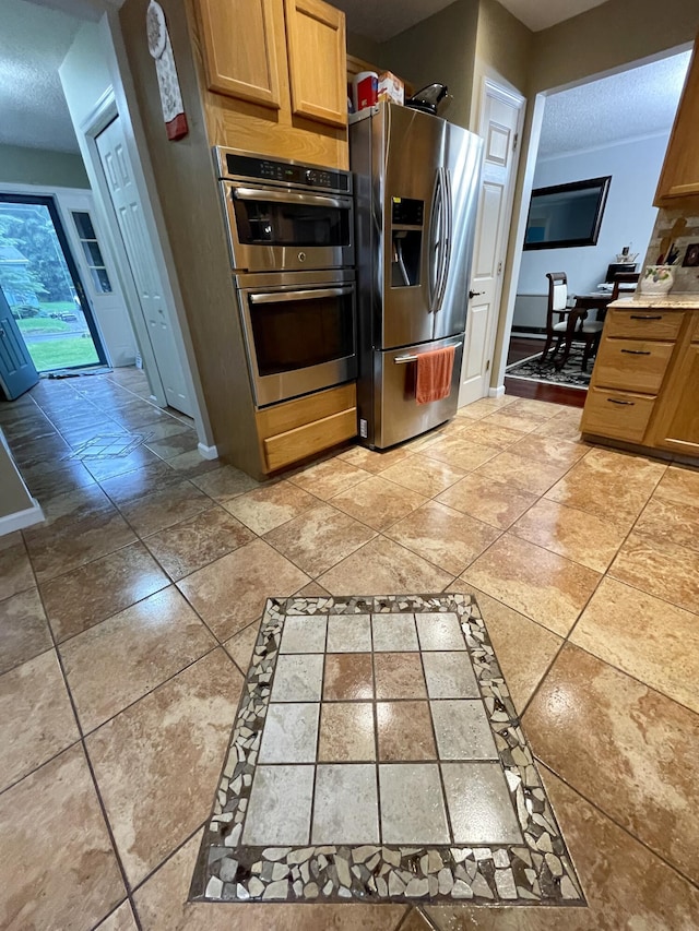 kitchen featuring a textured ceiling, stainless steel appliances, light countertops, and baseboards