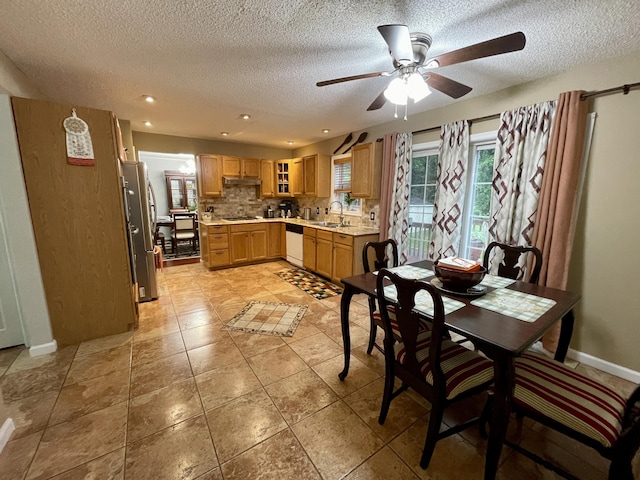 kitchen featuring light countertops, freestanding refrigerator, a sink, dishwasher, and under cabinet range hood