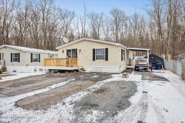 manufactured / mobile home with driveway, fence, a deck, and a carport