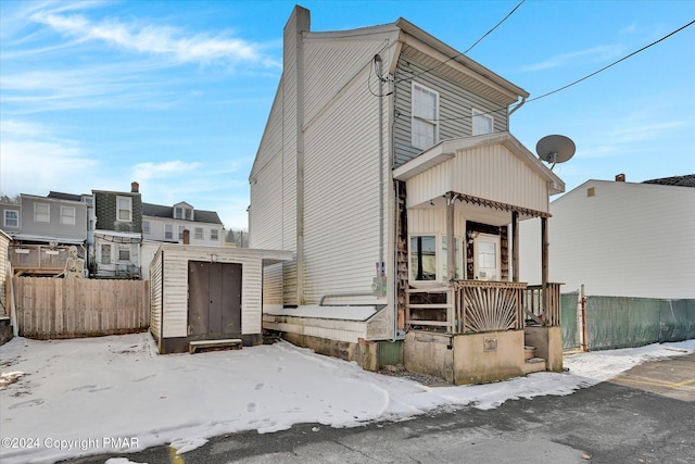 view of front facade featuring a storage shed, fence, a porch, and an outdoor structure