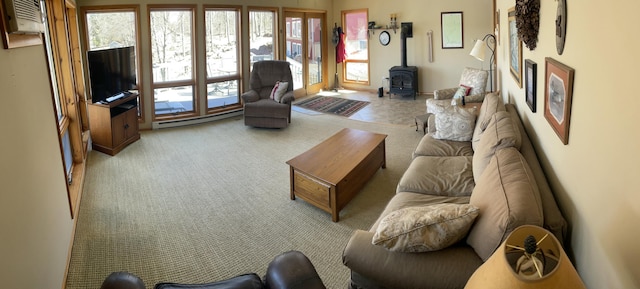 living area with a baseboard heating unit, a wood stove, carpet flooring, and a wall unit AC