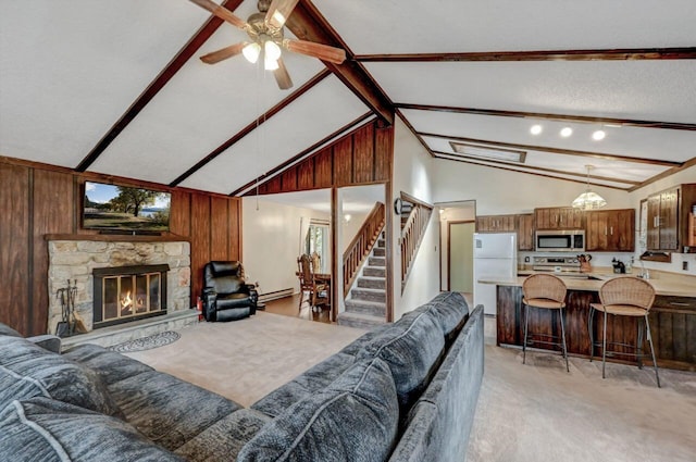 living area featuring wood walls, a fireplace, light colored carpet, ceiling fan, and stairs