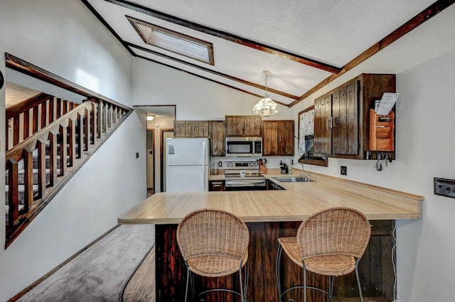 kitchen with vaulted ceiling with beams, light countertops, carpet flooring, stainless steel appliances, and a sink