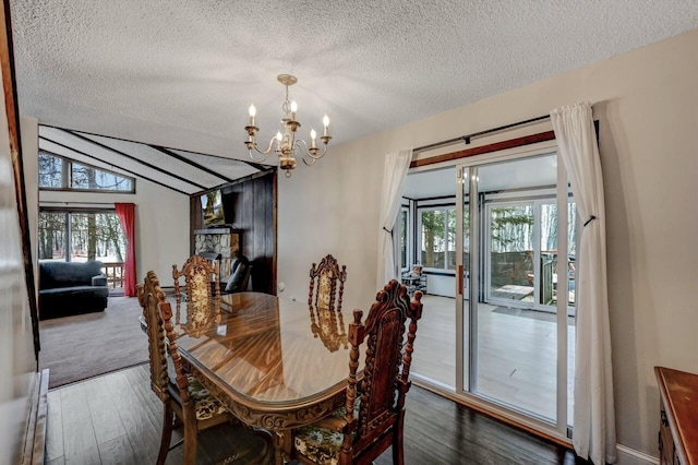 dining area with a textured ceiling, an inviting chandelier, wood finished floors, and vaulted ceiling