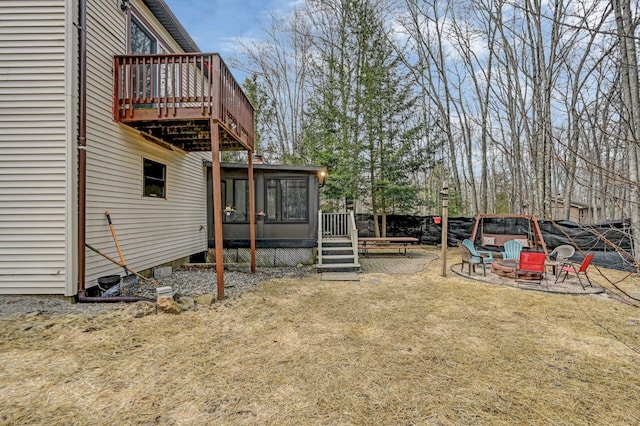 view of yard featuring a wooden deck, a fire pit, and a sunroom