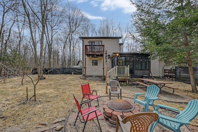 back of property with fence, a sunroom, and an outdoor fire pit