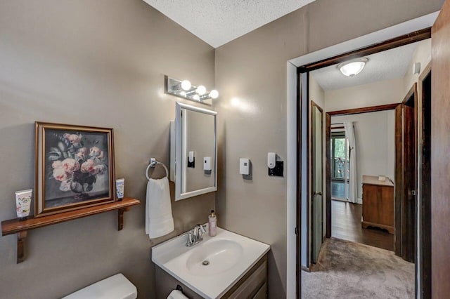 bathroom featuring a textured ceiling, toilet, and vanity