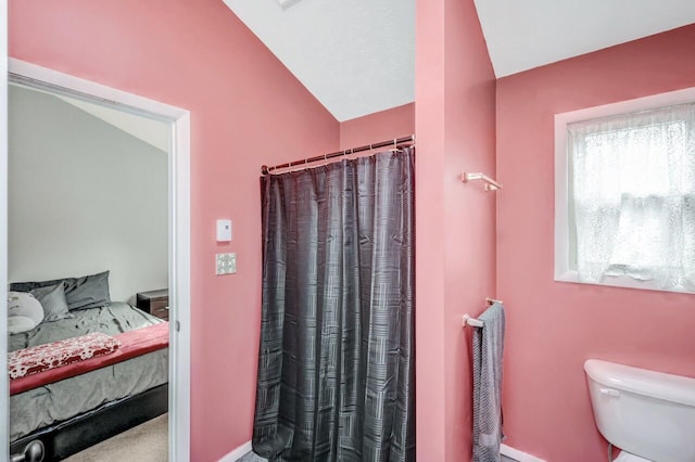 ensuite bathroom featuring connected bathroom, toilet, and a shower with shower curtain