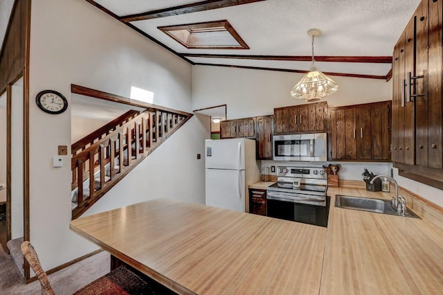 kitchen with a peninsula, a sink, light countertops, vaulted ceiling, and appliances with stainless steel finishes