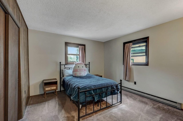 bedroom with carpet flooring, baseboard heating, and a textured ceiling