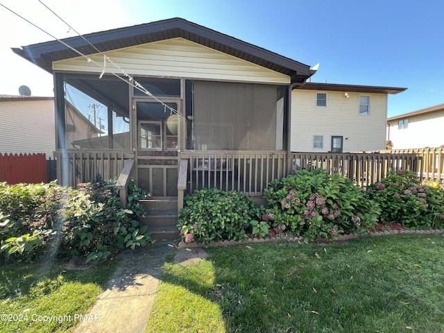 view of home's exterior with a sunroom, fence, and a yard