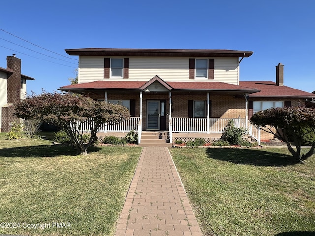 view of front of house featuring a porch, a front lawn, and brick siding