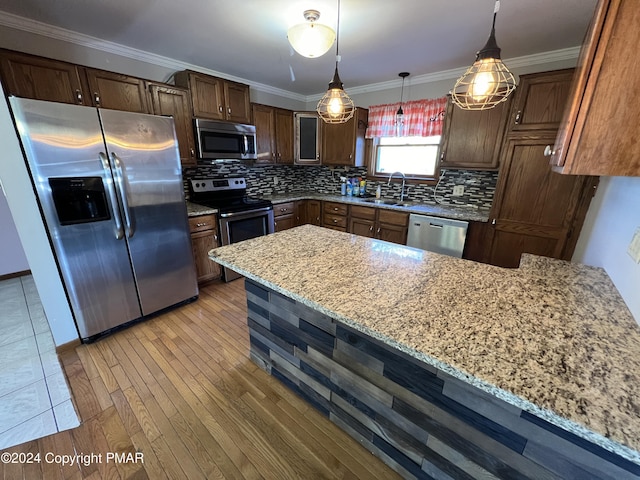 kitchen with stainless steel appliances, backsplash, light wood-style floors, light stone countertops, and a peninsula