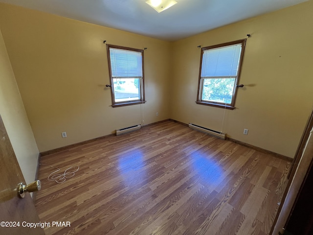 spare room with a baseboard radiator, wood finished floors, and a wealth of natural light