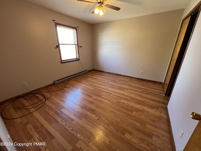 empty room with a baseboard heating unit, ceiling fan, baseboards, and wood finished floors