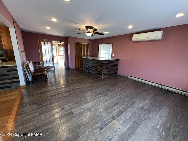 unfurnished living room with a wall unit AC, wood finished floors, and a wealth of natural light