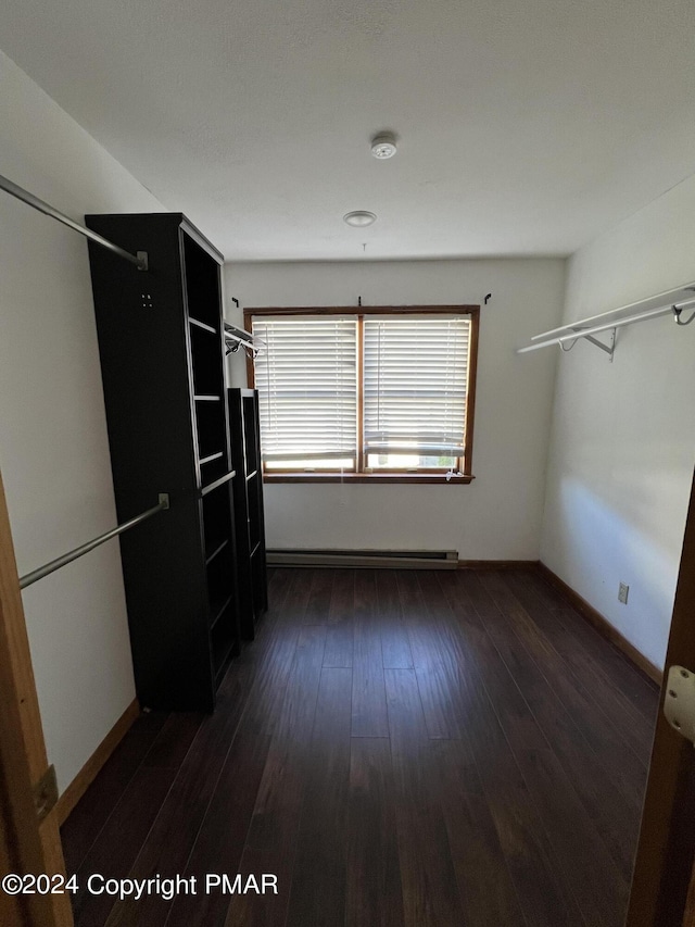 spacious closet with a baseboard heating unit and dark wood-type flooring