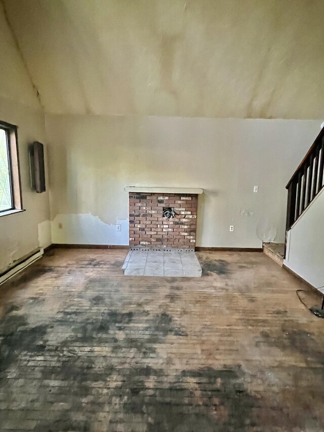 unfurnished living room featuring wood finished floors, vaulted ceiling, and baseboards