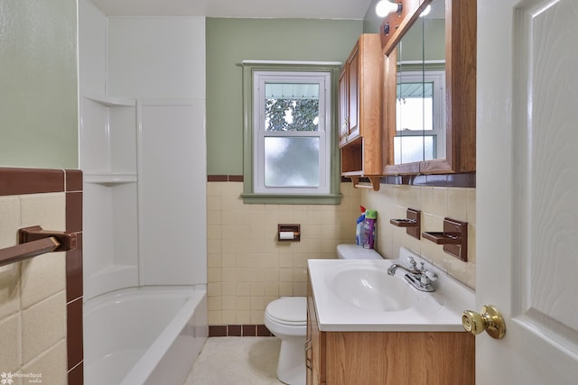 bathroom with tile walls, toilet, vanity, wainscoting, and tile patterned floors