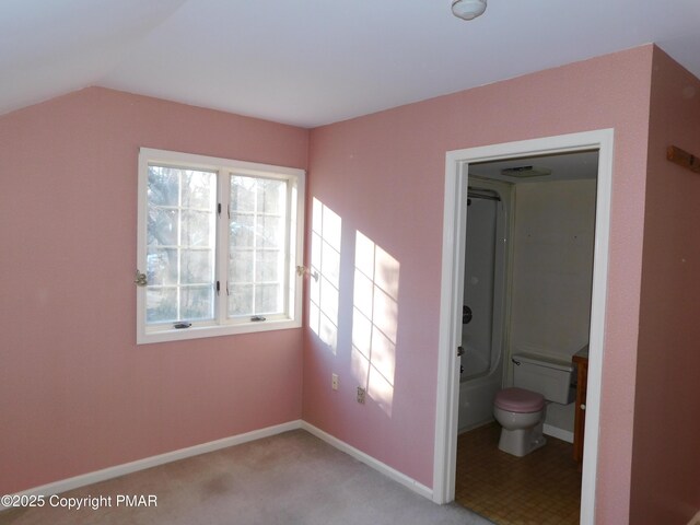 unfurnished bedroom with lofted ceiling, ensuite bath, and baseboards