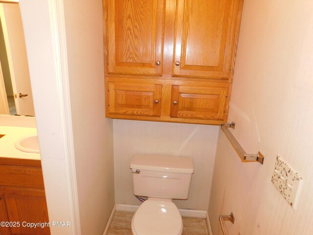 bathroom with baseboards, vanity, and toilet