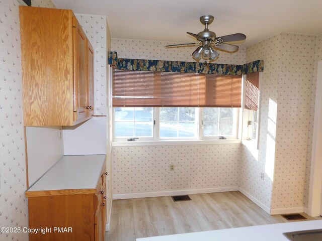 kitchen with light wood-style floors, visible vents, baseboards, and wallpapered walls