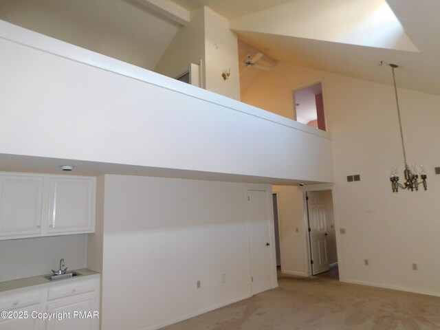 interior space with visible vents, light carpet, a sink, high vaulted ceiling, and ceiling fan with notable chandelier