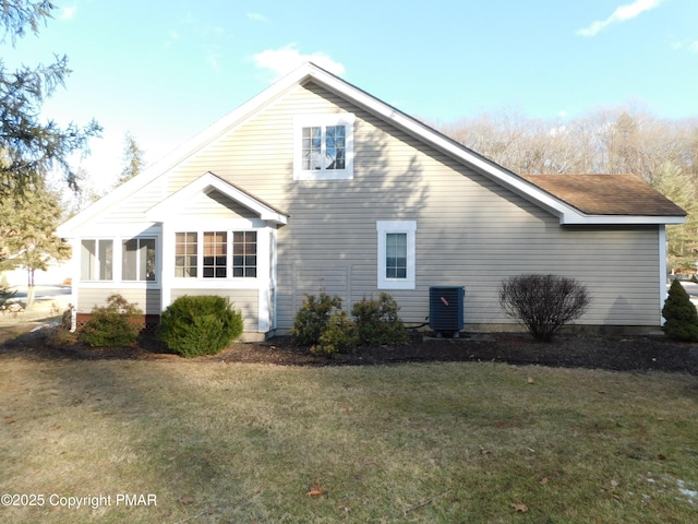 view of side of property featuring a sunroom, a lawn, and central AC