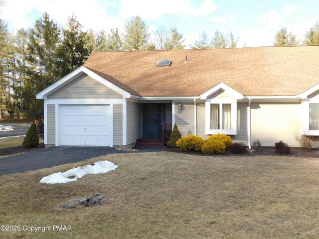 ranch-style house featuring a garage, a front yard, roof with shingles, and aphalt driveway