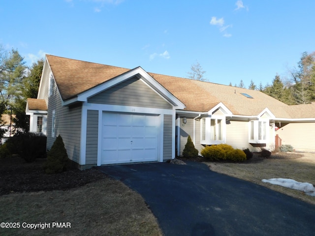 ranch-style house featuring an attached garage, driveway, and roof with shingles