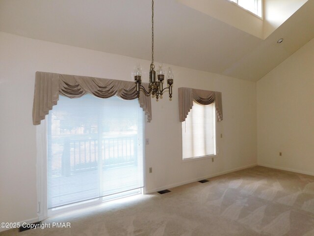 empty room featuring a chandelier, a healthy amount of sunlight, light colored carpet, and visible vents