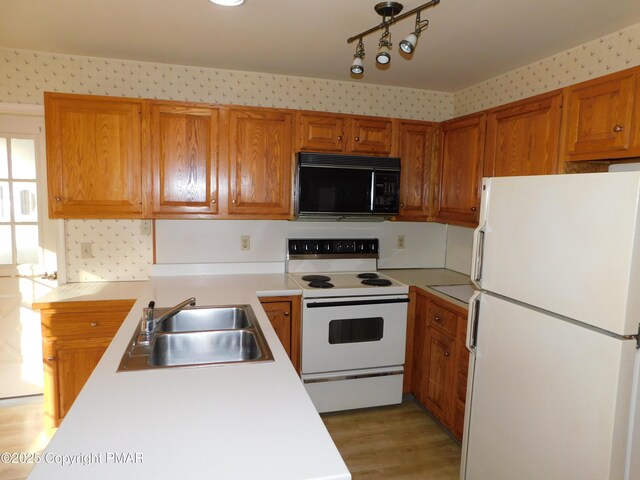 kitchen featuring light countertops, white appliances, a sink, and wallpapered walls